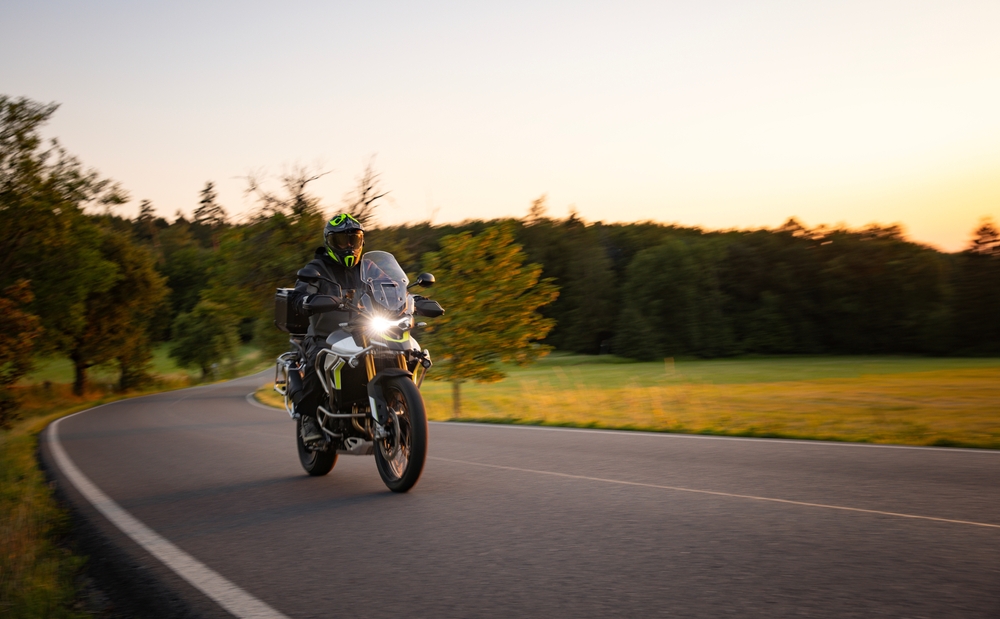 Driver Riding Motorcycle on Empty Road During Sunset.