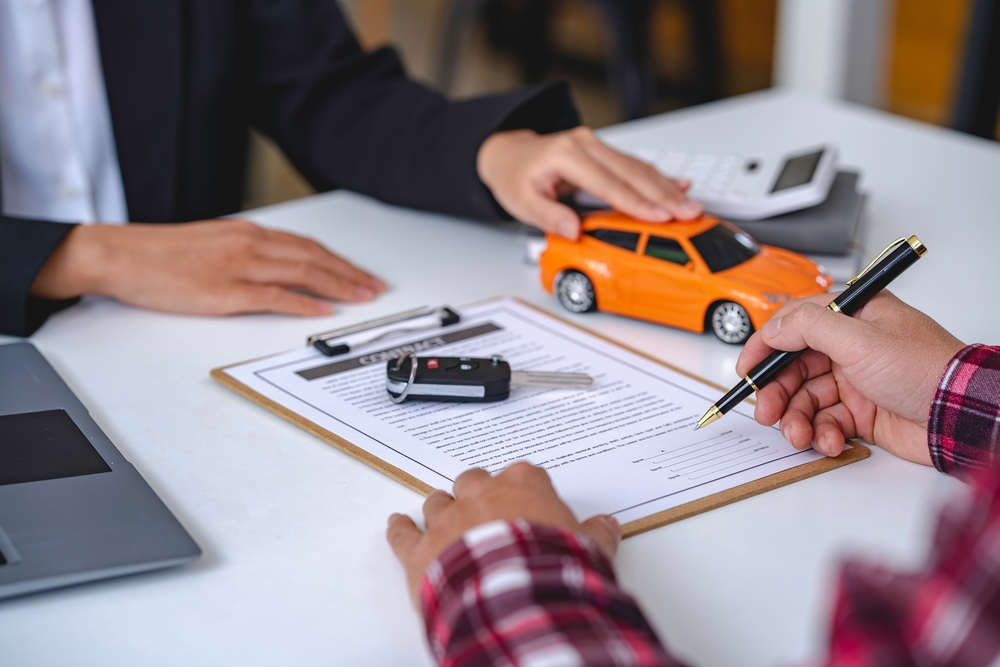 Insurance officer handing car keys to a customer as part of an auto insurance policy agreement.