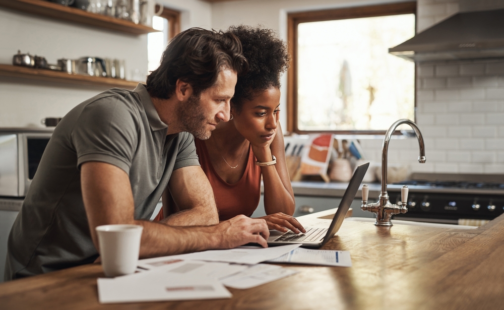Couple reviewing financial documents and insurance information while planning household finances.