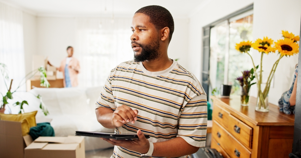 Homeowner using a tablet while organizing belongings in a new home